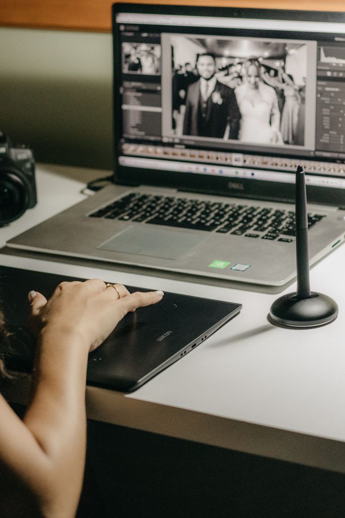 ours-journey Woman using a graphics tablet to edit wedding photos on a laptop.