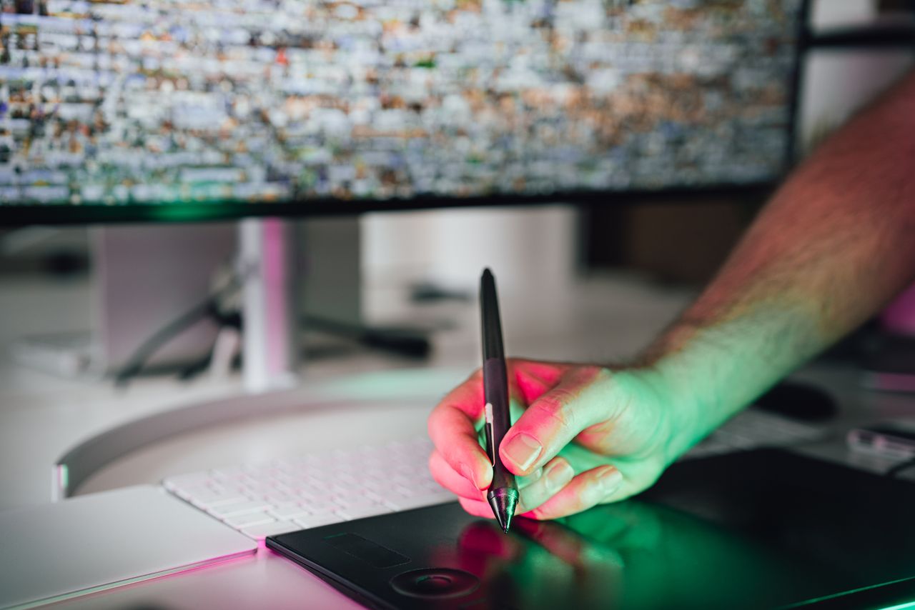 about-02 A digital artist using a graphics tablet and stylus in a modern workspace. High-tech creative process.